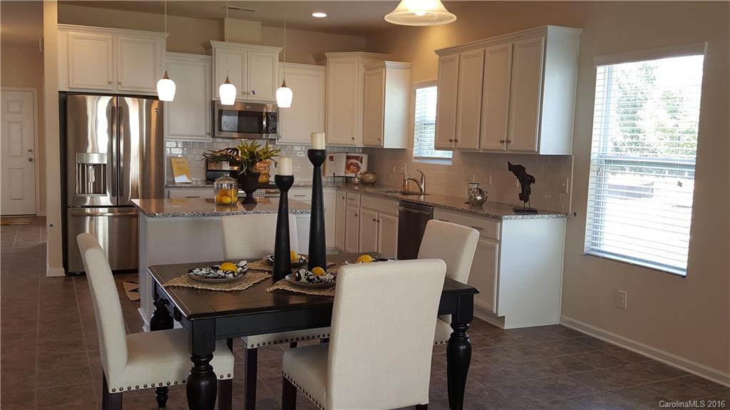 1628 Spring Blossom Trail, Unit SITE 18 Fort Mill, SC 29708 - Photo 11 of 22 a kitchen with a table chairs refrigerator and microwave