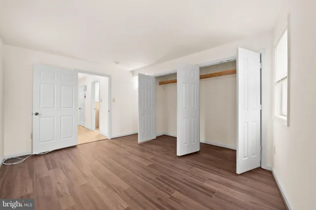 a view of an empty room with wooden floor and closet