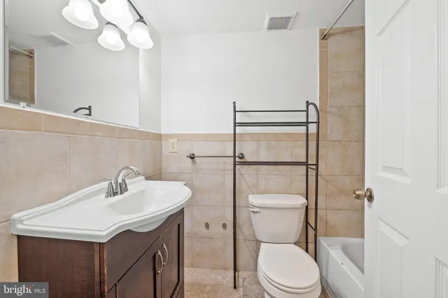 a bathroom with a toilet sink vanity and mirror