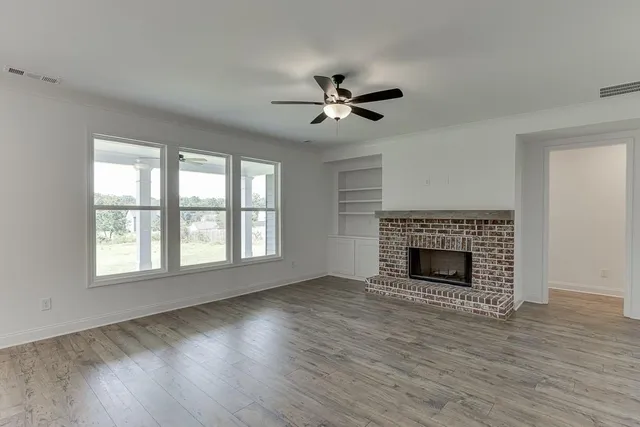 an empty room with wooden floor fireplace and windows