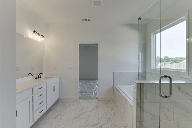 a spacious bathroom with a double vanity sink a mirror and a bathtub