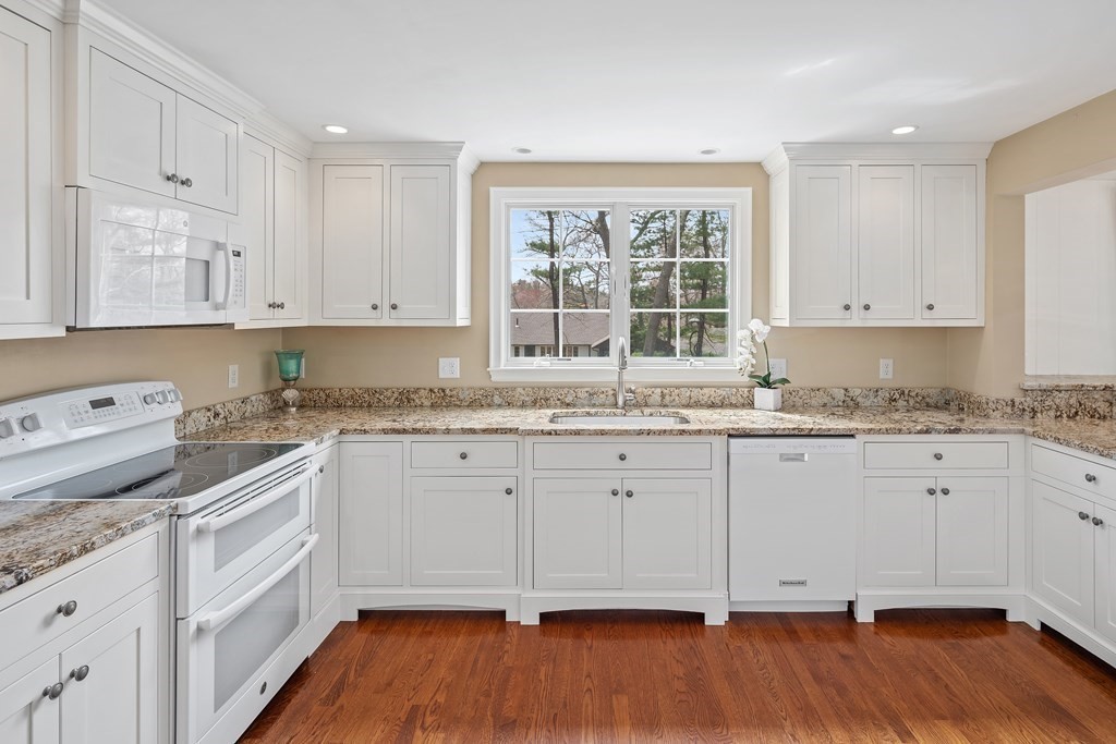 32 Howland Lane Hingham, MA 02043 - Photo 12 of 40 a kitchen with granite countertop white cabinets and white appliances with wooden floor
