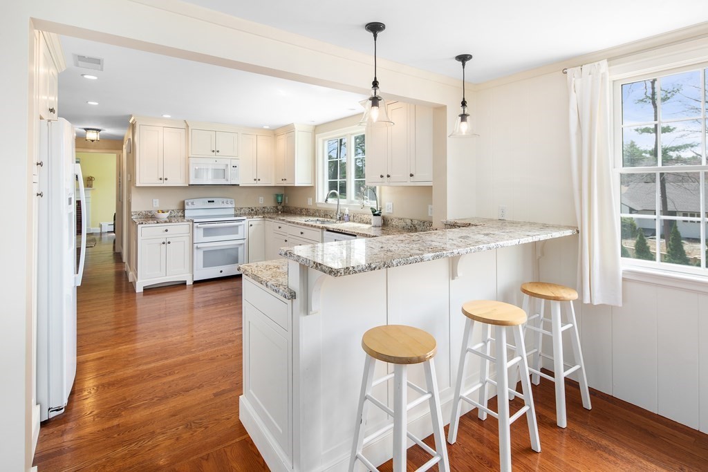 32 Howland Lane Hingham, MA 02043 - Photo 9 of 40 a kitchen with stainless steel appliances granite countertop a stove a refrigerator a sink a dining table and chairs with wooden floor