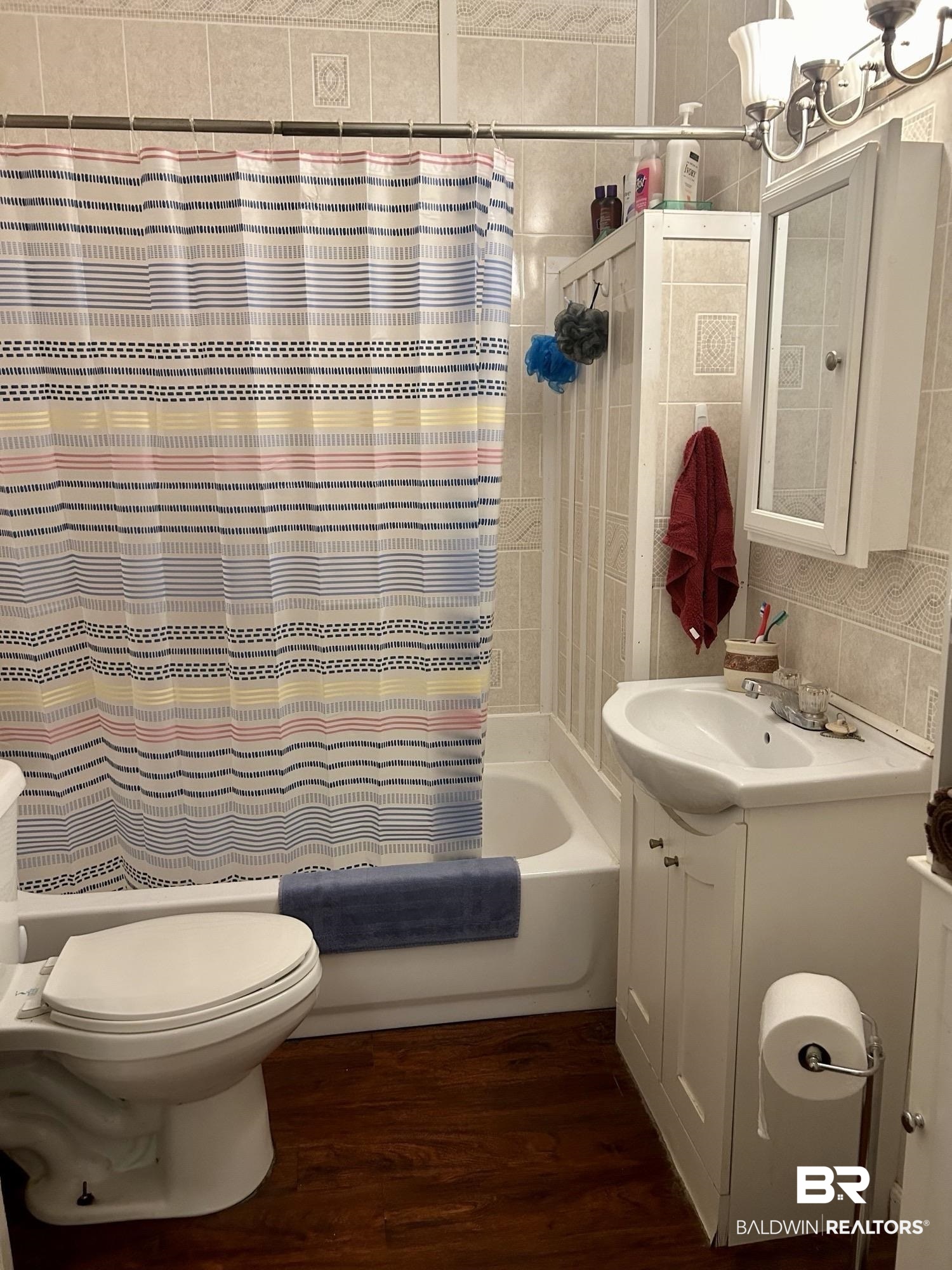 405 North Wasson Avenue Mobile, AL 36612 - Photo 14 of 26 Full bathroom featuring wood-type flooring, toilet, shower / tub combo with curtain, vanity, and tile walls