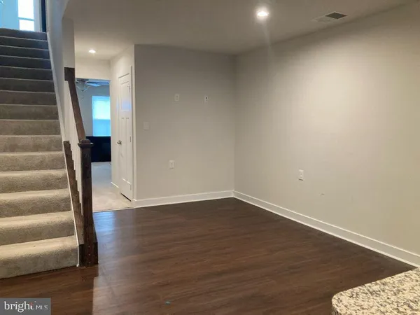 a view of an empty room with wooden floor and stairs