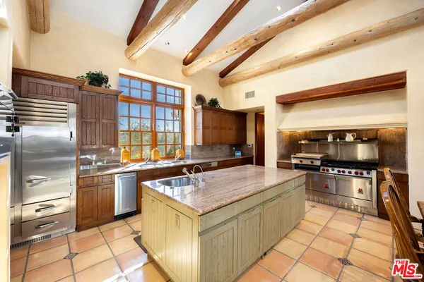 a kitchen with stainless steel appliances granite countertop a stove a refrigerator a dining table and chairs with wooden floor