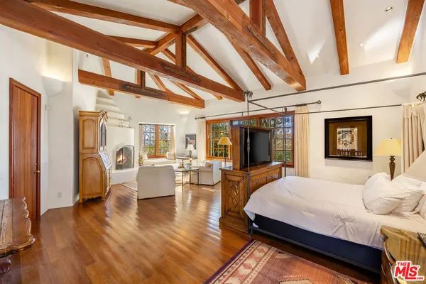 a spacious bedroom with a bed and wooden floor
