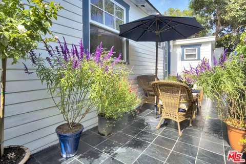 a view of a chair and table in backyard with potted plants