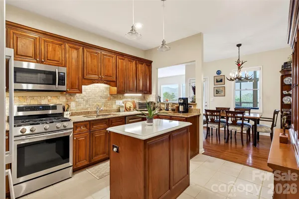 a kitchen with stainless steel appliances granite countertop a stove top oven a sink dishwasher a dining table and chairs with wooden floor