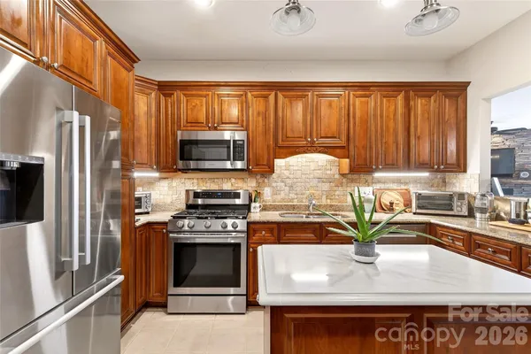 a kitchen with kitchen island granite countertop a stove sink and refrigerator