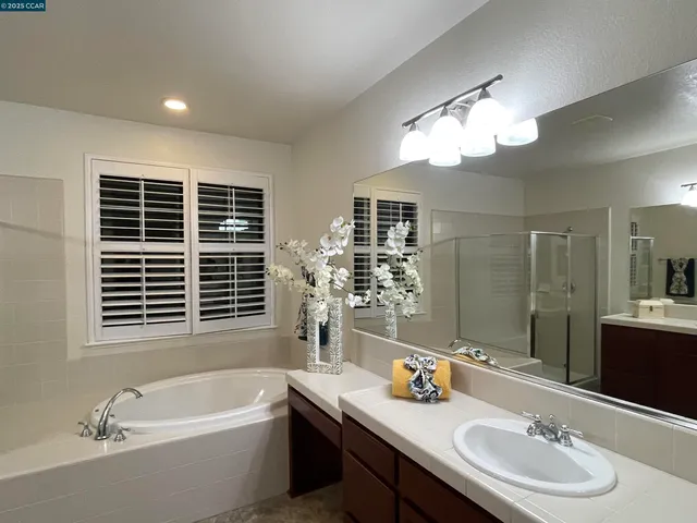 a bathroom with a tub double sink window and mirror