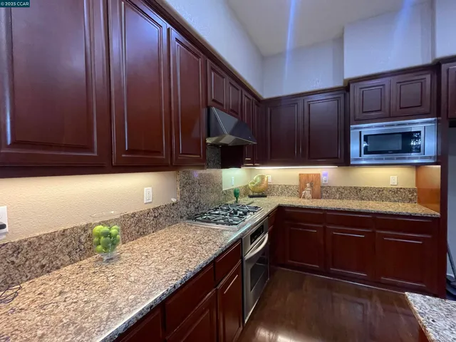 a kitchen with granite countertop wooden cabinets a sink and dishwasher