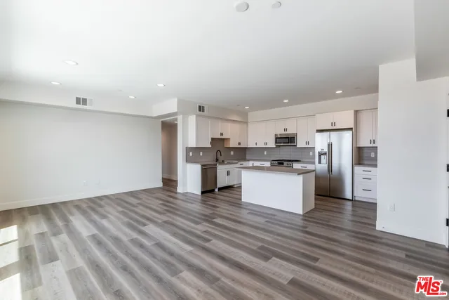a view of kitchen with granite countertop cabinets and refrigerator