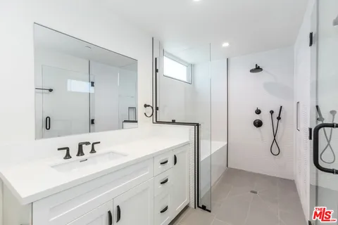 a bathroom with a sink vanity granite tub shower and a mirror