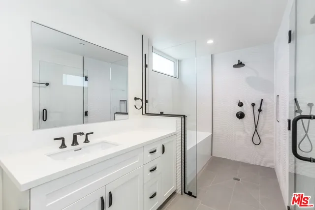 a bathroom with a sink vanity granite tub shower and a mirror