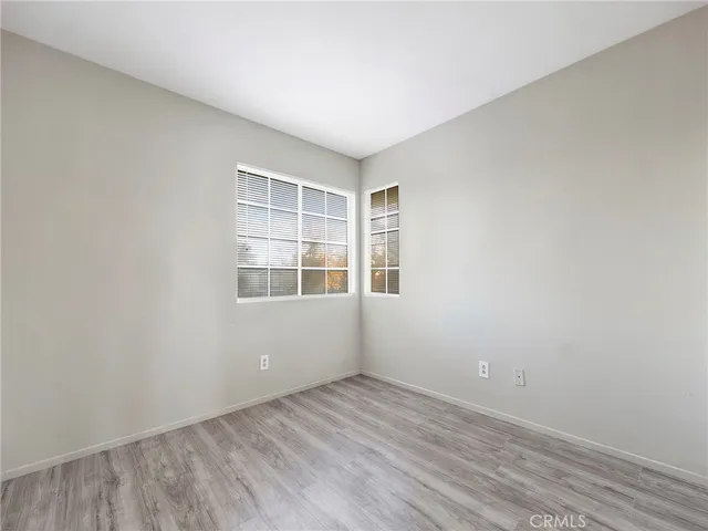 a view of an empty room with wooden floor and closet