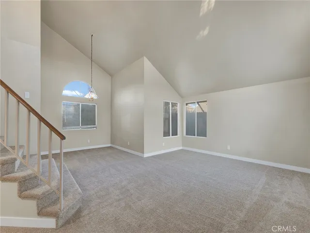 a view of an empty room with stairs and chandelier fan