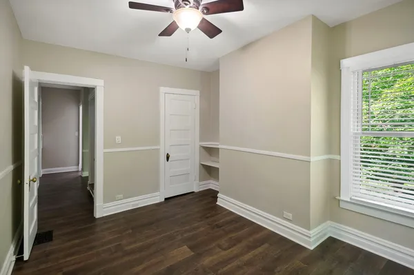 an empty room with wooden floor cabinet and windows