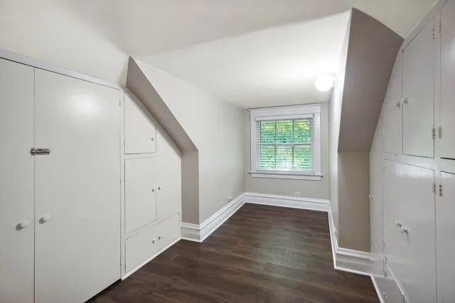 an empty room with wooden floor cabinet and windows