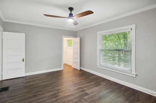a view of an empty room with wooden floor and a window