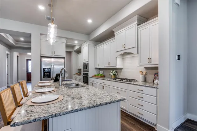a kitchen with granite countertop a sink a stove and cabinets