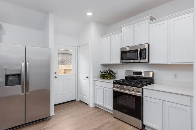 a kitchen with stainless steel appliances white cabinets a stove a microwave and a refrigerator