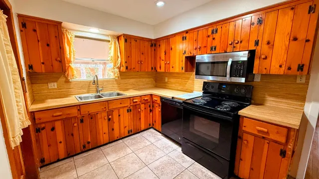 a kitchen with stainless steel appliances granite countertop a stove top oven a sink dishwasher and wooden cabinets with wooden floor