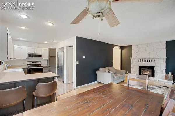 a large white kitchen with a stove a refrigerator a dining table and chairs with wooden floor