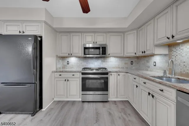 a kitchen with granite countertop white cabinets and stainless steel appliances