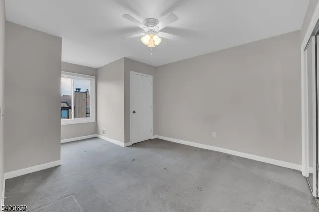 an empty room with a ceiling fan and a window