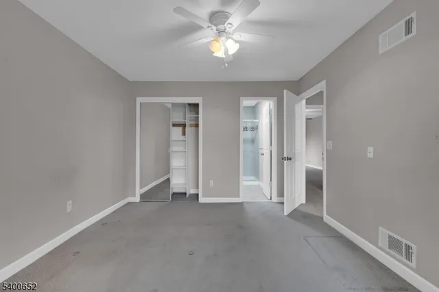 an empty room with closet and a ceiling fan