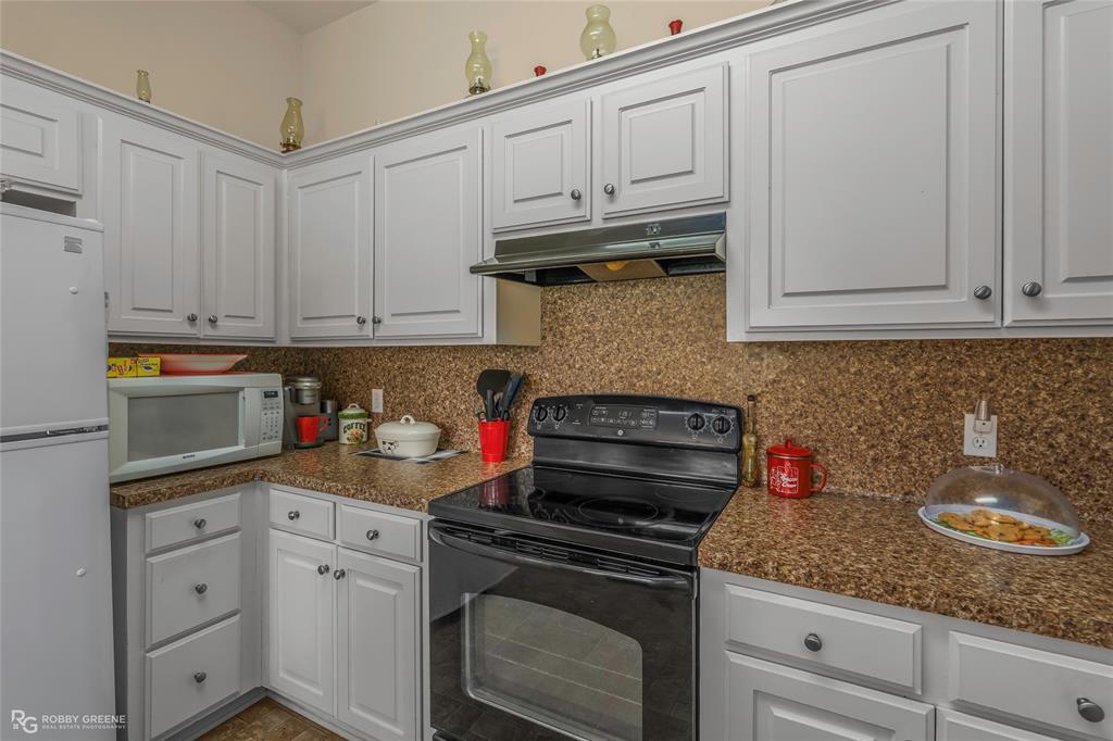 7193 Laurel Ridge Drive Greenwood, LA 71033 - Photo 30 of 40 Kitchen featuring white appliances, white cabinetry, and tasteful backsplash