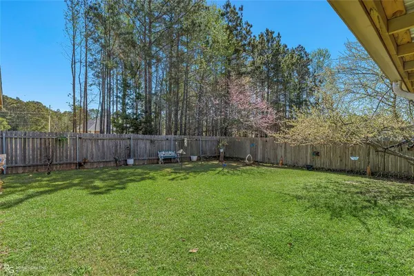 a view of a backyard with large trees and wooden fence