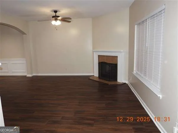 an empty room with wooden floor fan and windows
