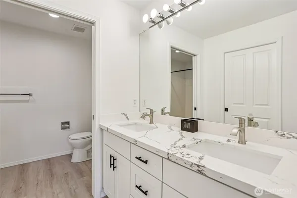 a bathroom with a double vanity sink toilet and a mirror