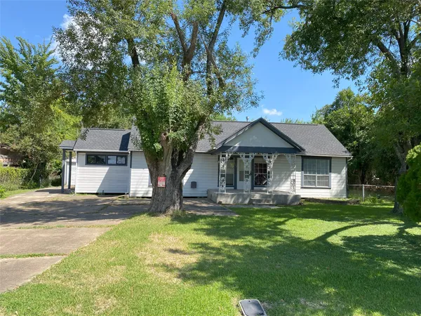 a front view of a house with a yard and a tree