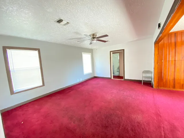 an empty room with windows and closet area