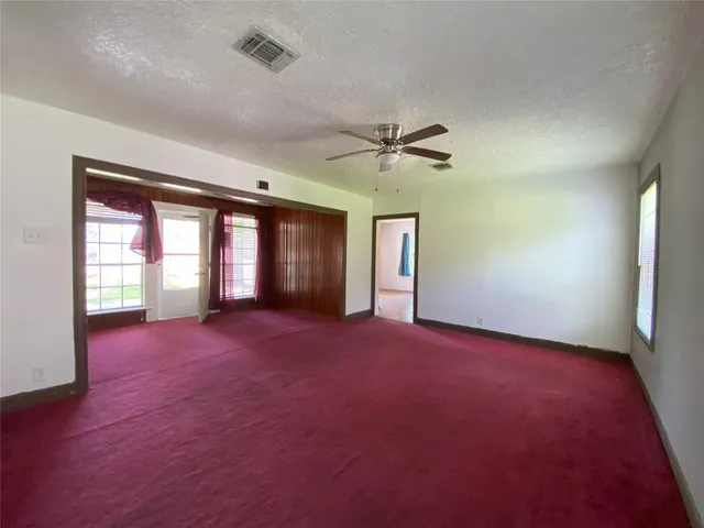 an empty room with windows and ceiling fan