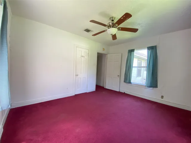 an empty room with ceiling fan and window