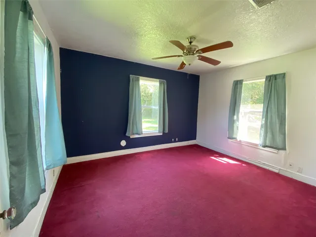 an empty room with windows and fan