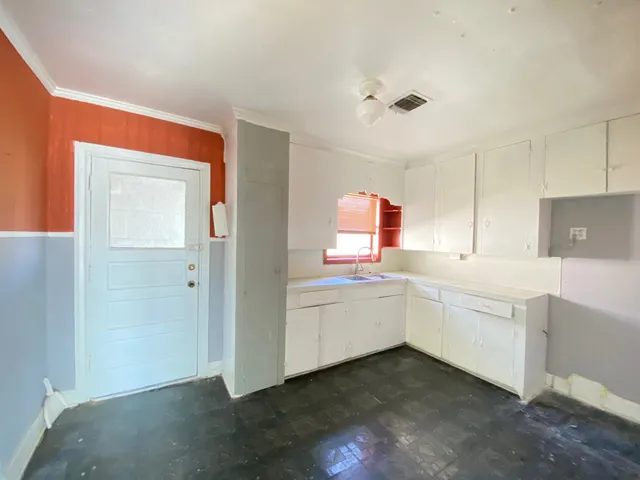 a kitchen with white cabinets and sink