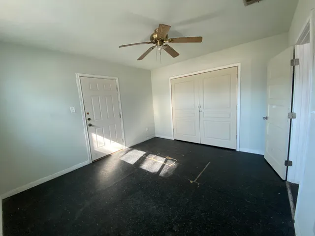 an empty room with wooden floor fan and windows