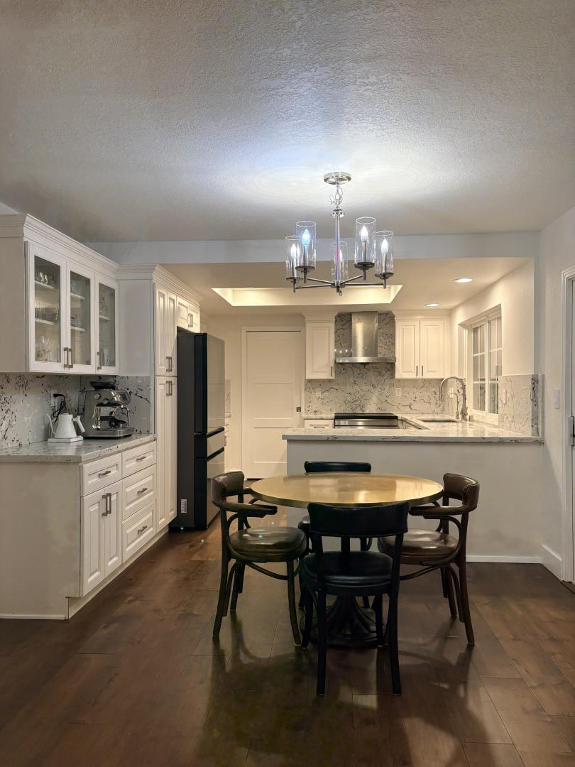 a kitchen with stainless steel appliances kitchen island granite countertop a table chairs sink and cabinets