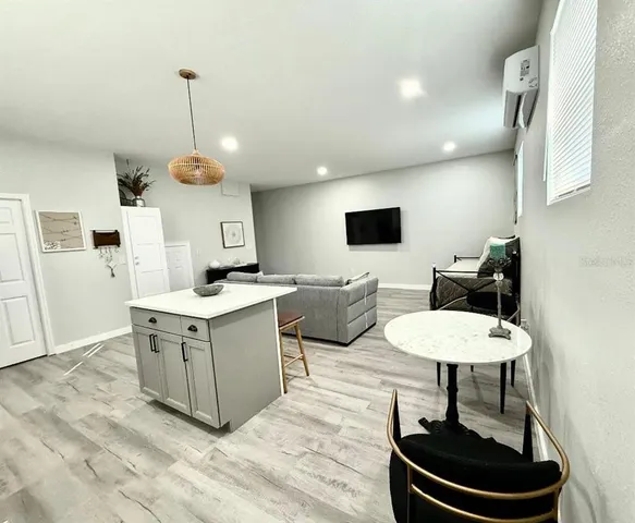 a living room with stainless steel appliances kitchen island granite countertop a sink a stove and a wooden floors