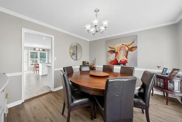 a view of a room with wooden floor chandelier and a kitchen