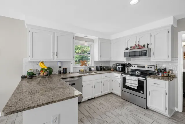 a kitchen with granite countertop a sink window and cabinets