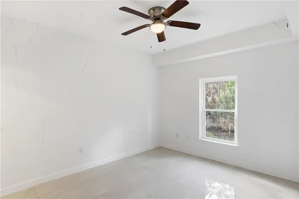 an empty room with windows and fan