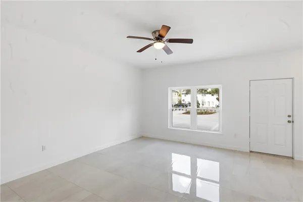 an empty room with windows and fan