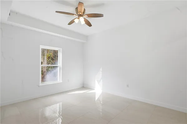 an empty room with windows and fan