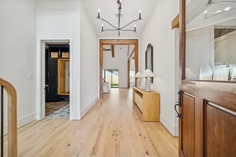a view of a hallway with wooden floor and a bathroom